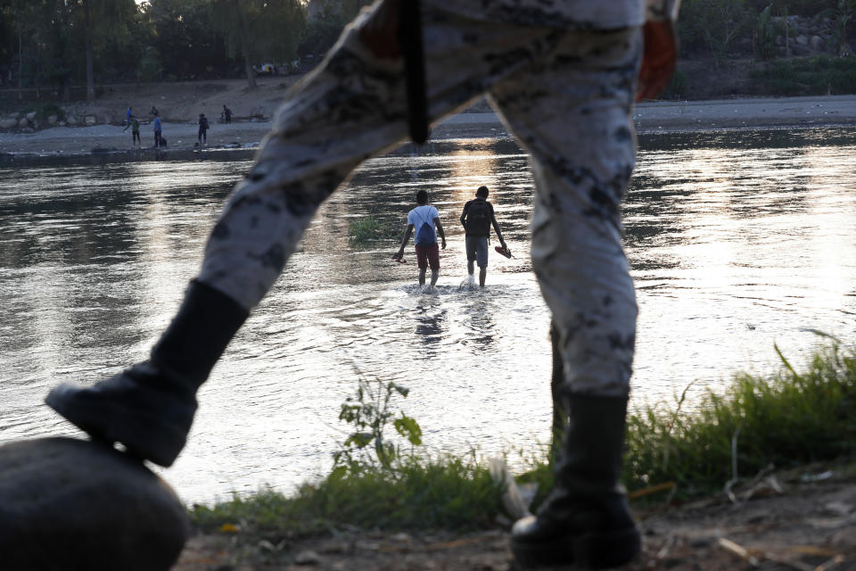 Migrantes hondureños que trataron de ingresar a México a pie regresan al lado guatemalteco del río Suchiate vigilados por un agente de la Guardia Nacional de México cerca de Ciudad Hidalgo, México, el miércoles 22 de enero de 2020. (AP Foto/Marco Ugarte)