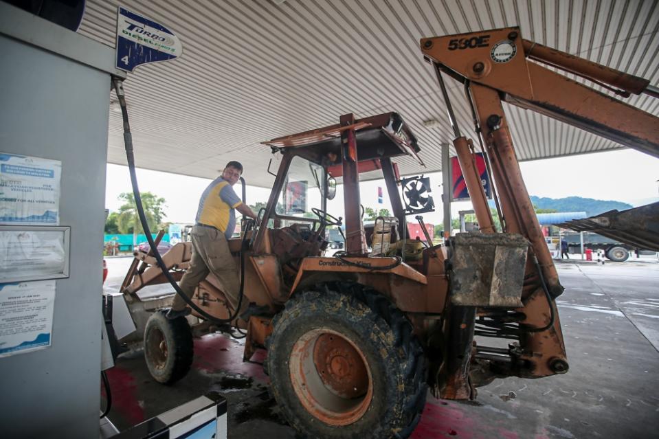 A man refuels his excavator at a gas station in Khantan Perak on June 10, 2024. — Picture by Farhan Najib