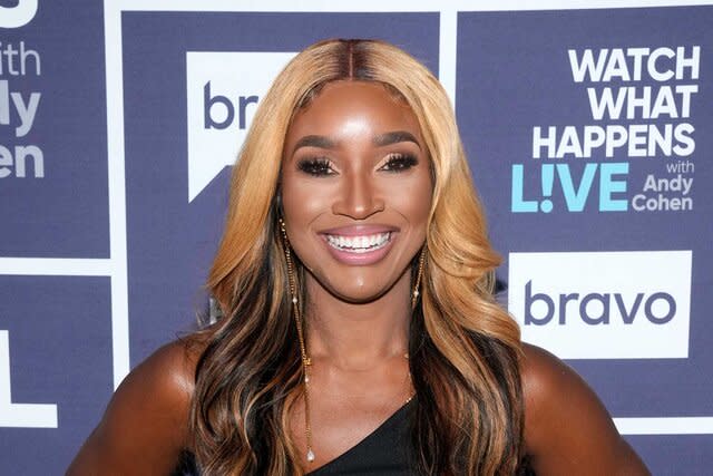 Contessa smiling in a black dress in front of the WWHL step and repeat.