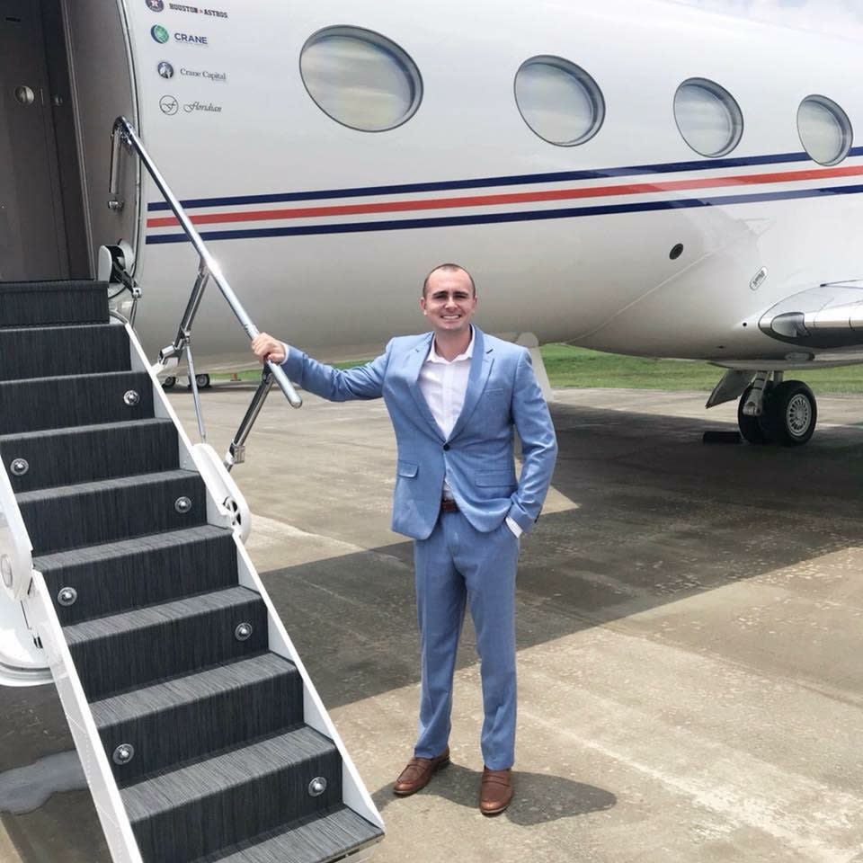 Kyle McLaughlin standing next to a private plane with logos for the Houston Astros and two companies owned by Jim Crane, Crane Worldwide Logistics and Crane Capital Group.