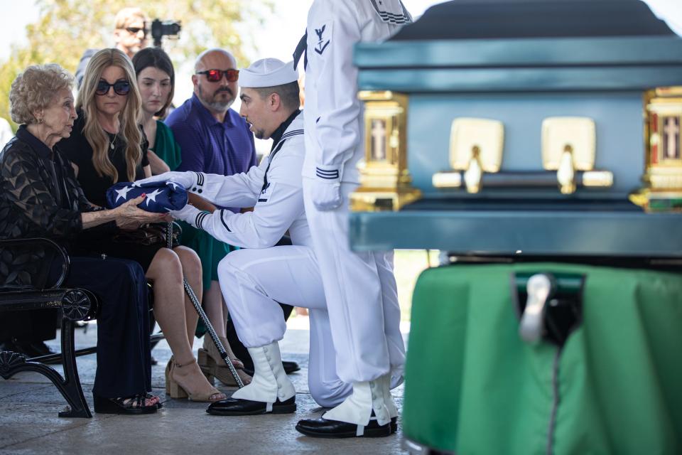 U.S. Navy Hospital Corpsman Third Class Christian Aranda hands Hilda Batterson the flag that draped the casket of husband Capt. Robert "Bob" Batterson during his funeral at the Coastal Bend State Veterans Cemetery on Wednesday, Aug. 30, 2023, in Corpus Christi, Texas.