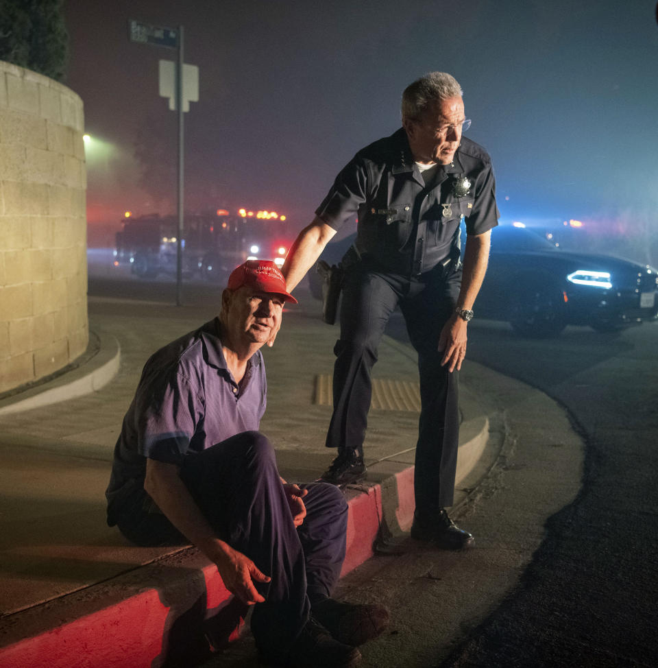 Los Angeles Police Department Chief Michel Moore tells resident Jerry Rowe that firefighters are coming after the roof of Rowe's home caught fire from the Saddleridge fire in Granada Hills, Calif., Friday, Oct. 11, 2019. (AP Photo/Michael Owen Baker)