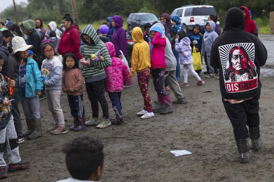 Maverick Chailes, 12, right, returns to a game line with children while attending the carnival, Thursday, Aug. 17, 2023, in Akiachak, Alaska. The village hosted a multiday carnival with games and prizes for the village youth. (AP Photo/Tom Brenner)