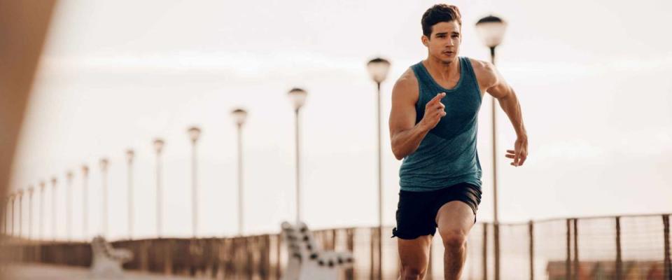 Full length shot of healthy young man running on the promenade. Male runner sprinting outdoors.