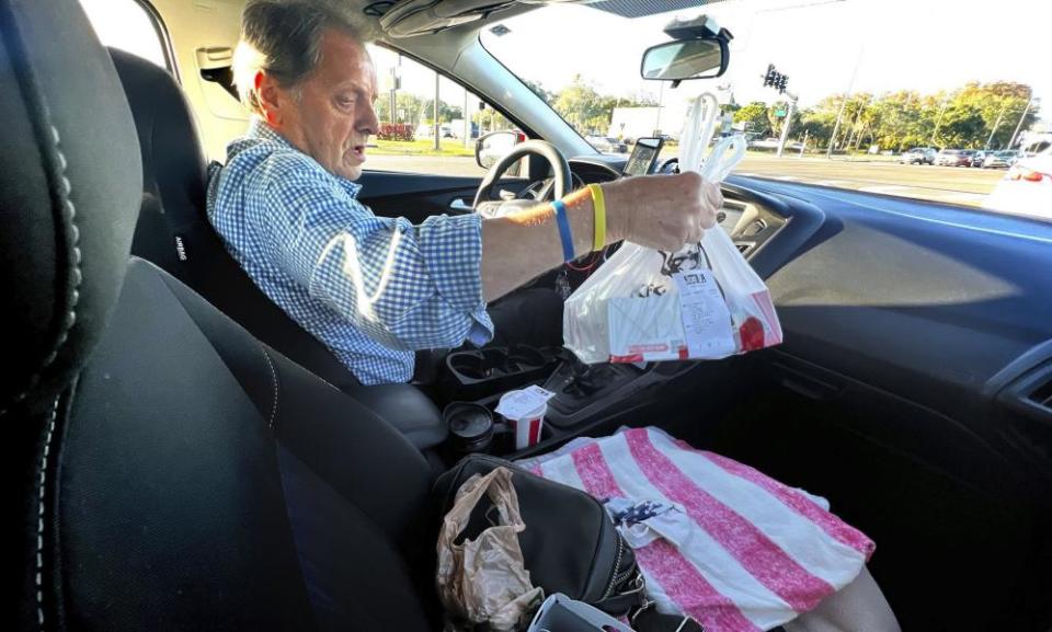 Nevin Overmiller, 78, examines an order of KFC while delivering the meal for Uber Eats to supplement his retirement income.