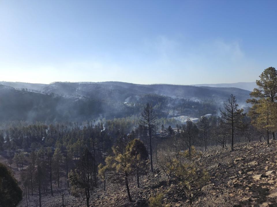 Smoke rises along a hillside in the Village of Ruidoso, N.M., on Wednesday, April 13, 2022. Officials say a wildfire has burned about 150 structures, including homes, in the New Mexico town of Ruidoso. (Alexander Meditz via AP)