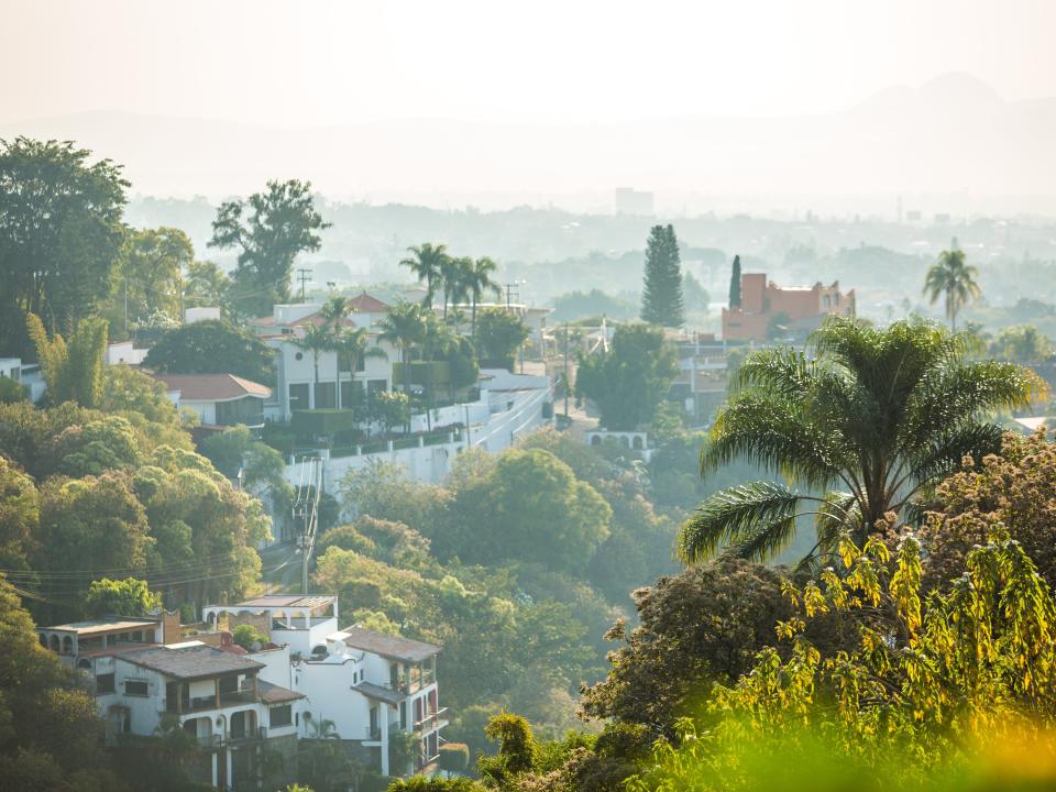 Mexican town of Cuernavaca, shot from a distance with vegetation surrounding it.