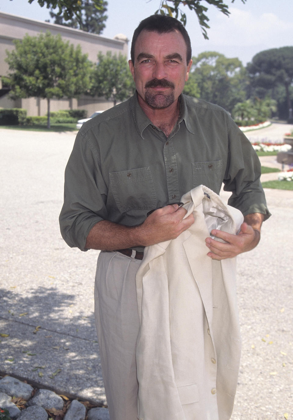 Tom Selleck holding a jacket standing outdoors