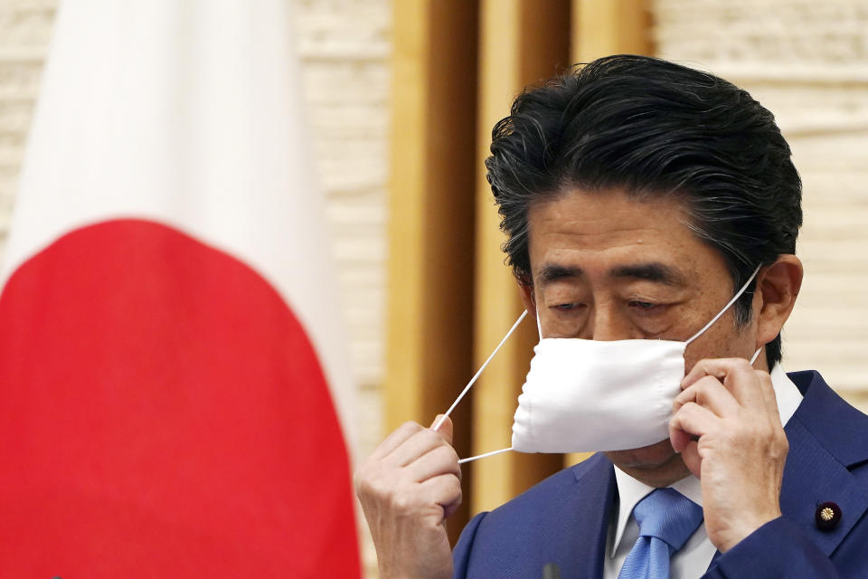 FILE - Then Japanese Prime Minister Shinzo Abe removes a face mask before speaking at a press conference at his official residence in Tokyo May 4, 2020. Former Japanese Prime Minister Abe, a divisive arch-conservative and one of his nation's most powerful and influential figures, has died after being shot during a campaign speech Friday, July 8, 2022, in western Japan, hospital officials said. (AP Photo/Eugene Hoshiko, File)