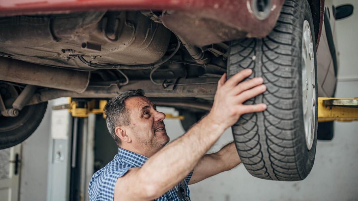 Auto mechanic repairing car at service, tire replacement.