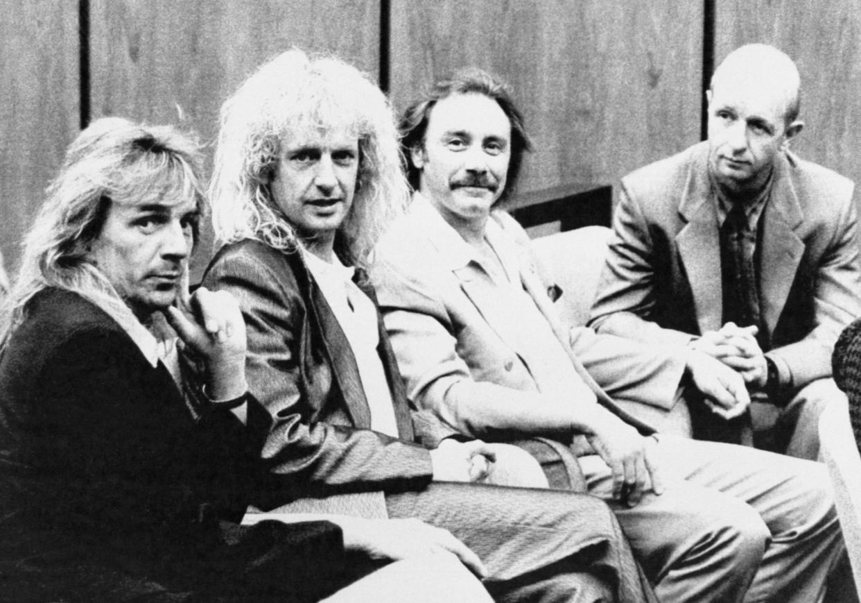 Judas Priest members Glenn Tipton, K.K. Downing, Ian Hill and Rob Halford sit together on courtroom bench.