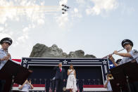 President Donald Trump, accompanied by first lady Melania Trump, stands during the national anthem with a flyover by the U.S. Navy Blue Angles at Mount Rushmore National Memorial, Friday, July 3, 2020, near Keystone, S.D. (AP Photo/Alex Brandon)