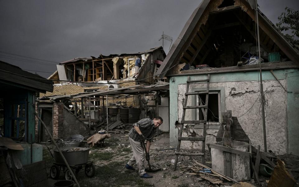 A man cleans his destroyed house after a strike in the city of Dobropillia - ARIS MESSINIS/AFP 