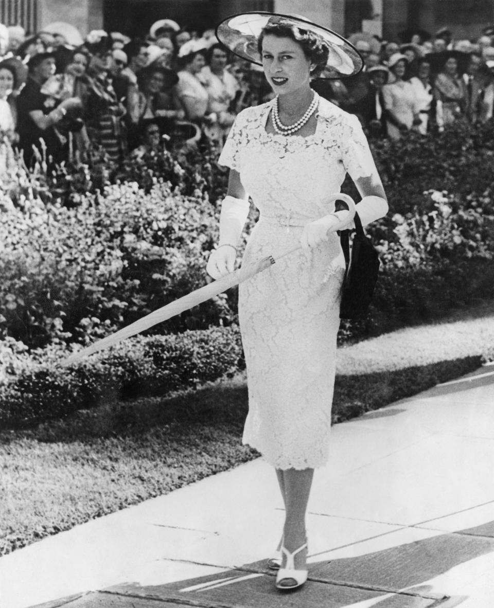Queen Elizabeth wearing a slim-fitting white lace dress and hat