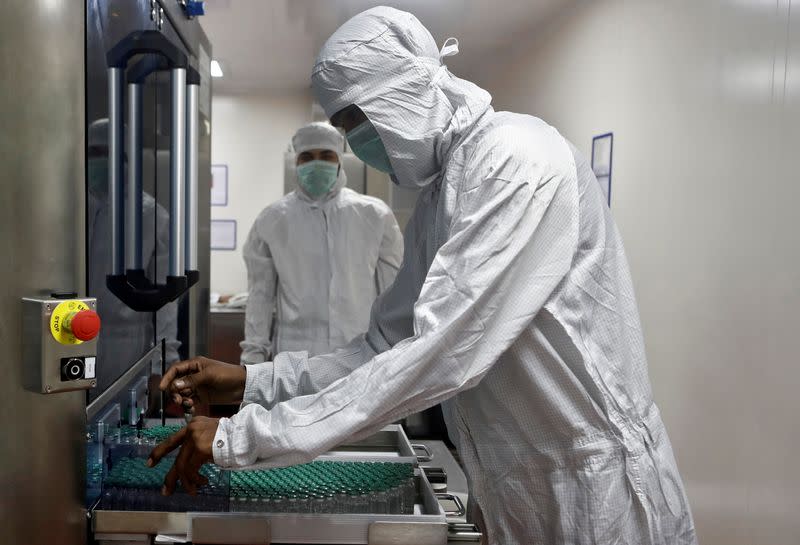 FILE PHOTO: An employee in personal protective equipment (PPE) removes vials of AstraZeneca's COVISHIELD, coronavirus disease (COVID-19) vaccine, from a visual inspection machine inside a lab at Serum Institute of India, Pune