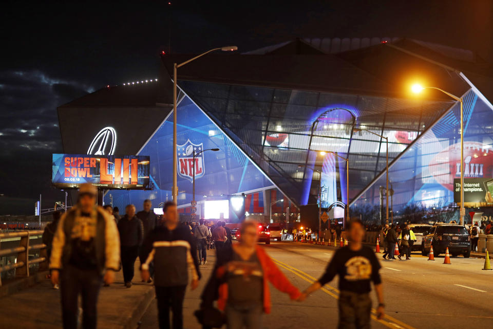 Pedestrians walk in front of Mercedes-Benz Stadium ahead of Sunday's NFL Super Bowl 53 football game between the Los Angeles Rams and New England Patriots in Atlanta, Saturday, Feb. 2, 2019. (AP Photo/David Goldman)