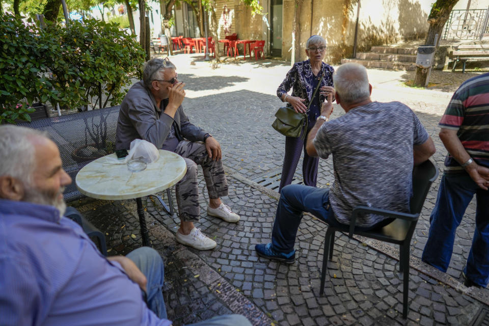 Rabbi Barbara Aiello, center, talks with residents of Serrastretta, southern Italy, as they sit at a caffe', Friday, July 8, 2022. From a rustic, tiny synagogue she fashioned from her family's ancestral home in this mountain village, American rabbi Aiello is keeping a promise made to her Italian-born father: to reconnect people in this southern region of Calabria to their Jewish roots, links nearly severed five centuries ago when the Inquisition forced Jews to convert to Christianity. (AP Photo/Andrew Medichini)