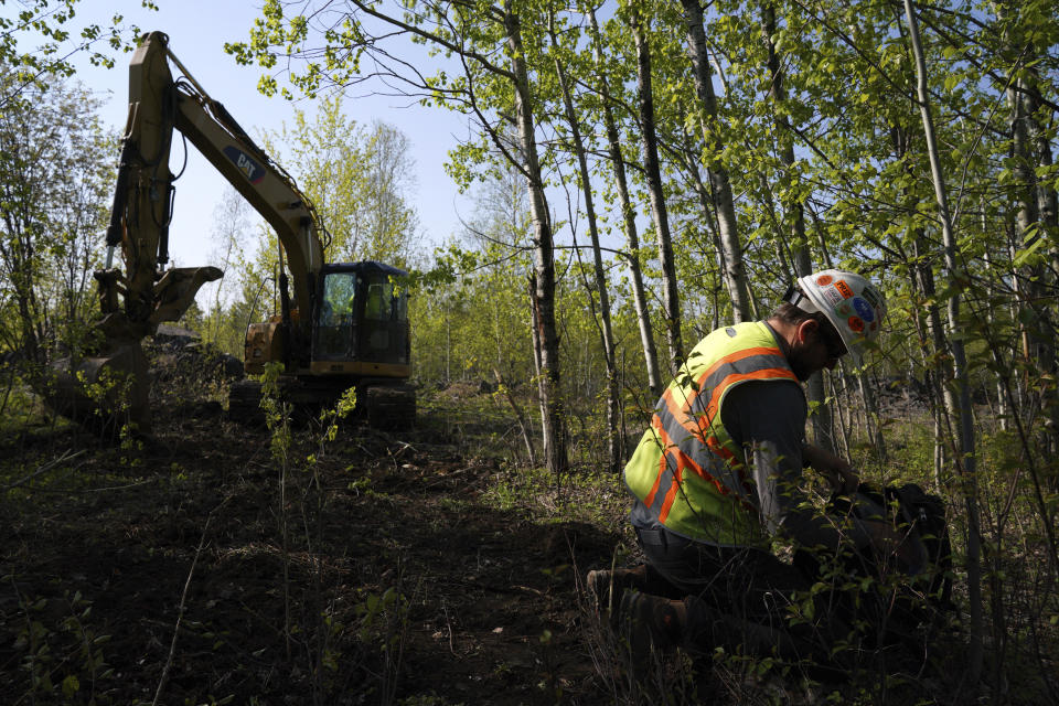 In this Wednesday, May 29, 2019, Eric Olson, right, gathers his tools as contractor Robert Radotich uses a backhoe to dig areas so the soil stratification can be observed which will help them engineer and design the infiltration pods for the Polymet copper-nickel mine in Hoyt Lakes, Minn. The developers of the proposed mine in northern Minnesota are courting bankers for nearly $1 billion to move ahead with the project, even as opponents hold out hope of blocking the operation due to fears of water pollution. (Anthony Souffle/Star Tribune via AP)