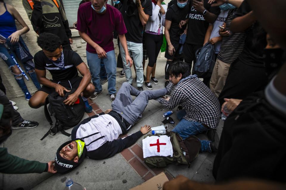 A man lies on the ground screaming as bystanders try to help