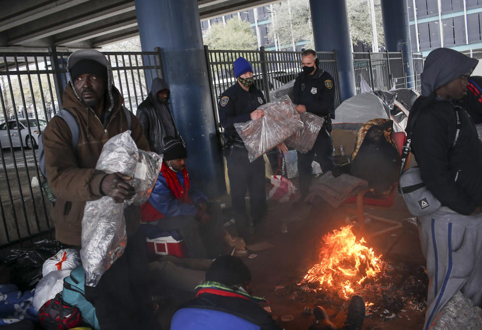 Houston Police officers Kenneth Bigger, center, and Aaron Day, center right, hand out blankets to people under the elevated portion of I-45 in downtown Houston, Tuesday, Feb. 16, 2021, as a winter weather continues to hit the area. (Jon Shapley/Houston Chronicle via AP)