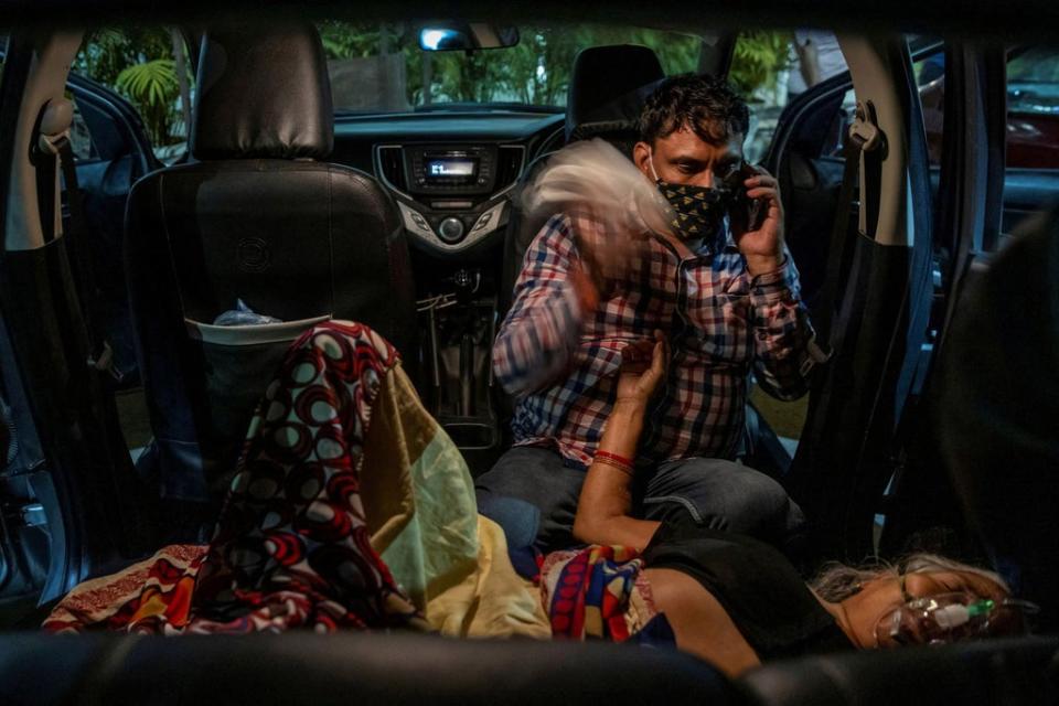 Manoj Kumar waves a handkerchief from the back seat of his vehicle at his mother Vidhya Devi as she receives oxygen in the parking lot of a Gurudwara in Ghaziabad on 24 April 2021 (Reuters/Danish Siddiqui)