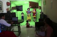 Circus clown Carlos Olazabal, 65, whose clown name is "Chiquitin," or Little One, center, performs with his family in a studio they set up in their home on the outskirts of Lima, Peru, Monday, Aug. 10, 2020. The Olazabal family started selling live, online performances for about $3 per viewer after the COVID-19 lockdown put an end to their live circus performances. (AP Photo/Martin Mejia)