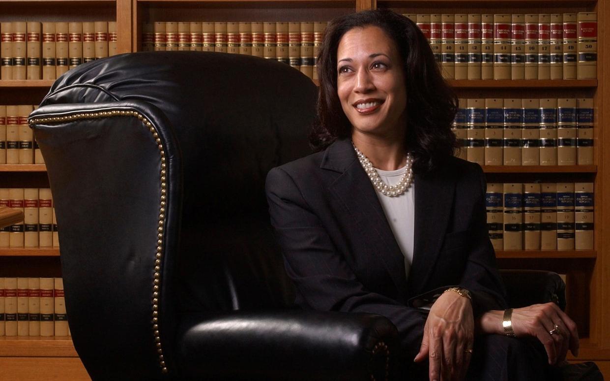 Ms Harris poses in a leather armchair in front of legal books