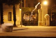 Cairo University students, who are supporters of the Muslim Brotherhood and ousted Egyptian President Mohamed Mursi, throw a tear gas canister towards Egyptian security forces from behind the university's gates, during a clash, in Cairo December 11, 2013. (REUTERS/Mohamed Abd El Ghany)