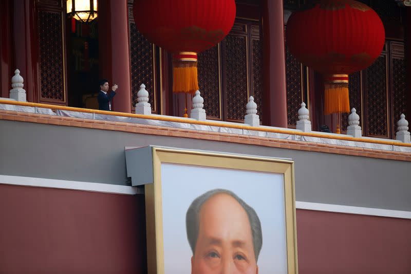 Security personnel holds his mobile phone at the Tiananmen Gate before a military parade marking the 70th founding anniversary of People's Republic of China, on its National Day in Beijing