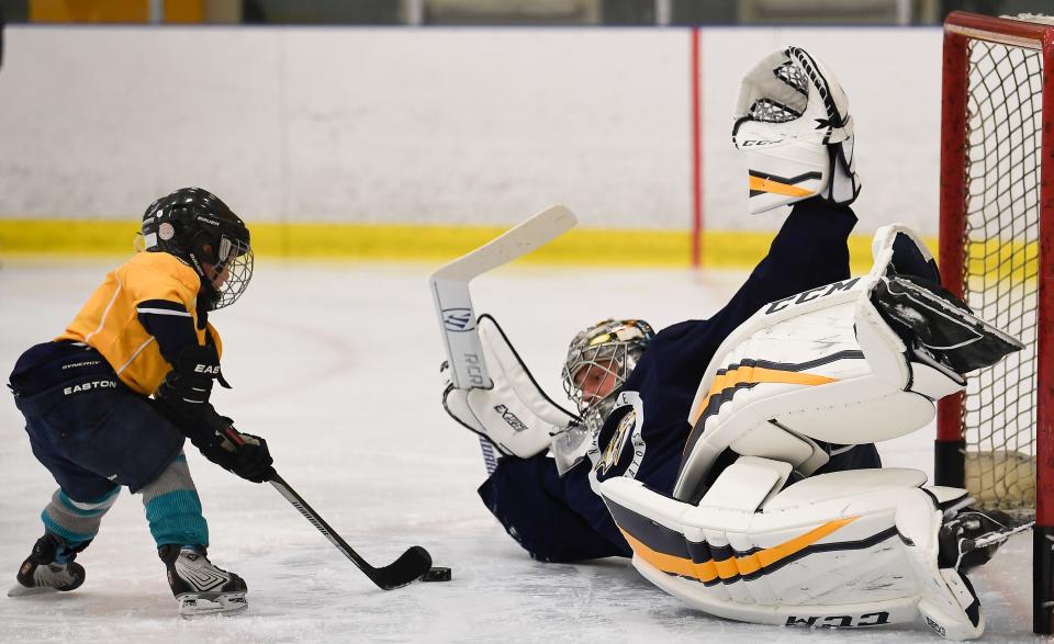 Knox Bentley 4, son of country music artist Dierks Bentley shoots a puck past Predators goalie Pekka Rinne (35) during a practice at Centennial Sportsplex Friday, March 30, 2018, in Nashville, Tenn. Bentley and his son were special guests of the team. 