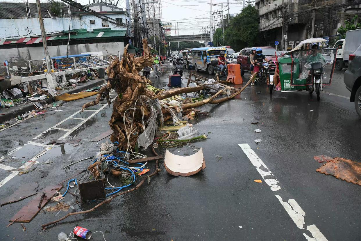 Motorists drive past a tree trunk washed along a street in Manila on July 25. 