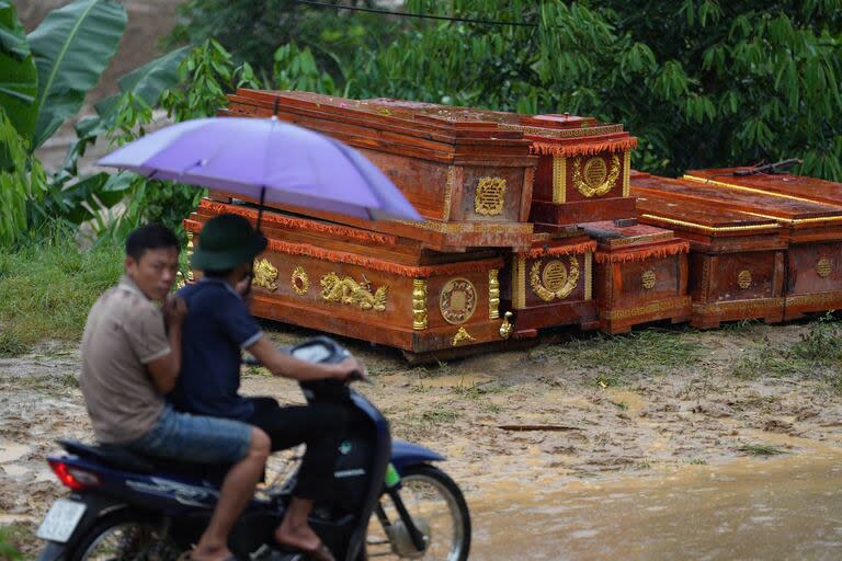 Hombres en una scooter pasan junto a ataúdes apilados para las víctimas de un deslizamiento de tierra en el remoto pueblo de montaña de Lang Nu, provincia de Lao Cai, el 11 de septiembre