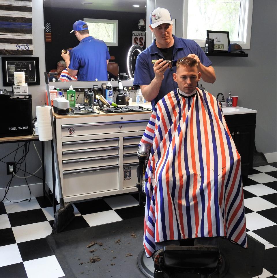 Tyler McKee cuts the hair of Robert Hill at McKee's Mancave Barbershop, opened recently on Ohio 83 near Lake Park. McKee was formerly in law enforcement, but grew up watching his grandfather, John McKee, cut hair in Downtown Coshocton.