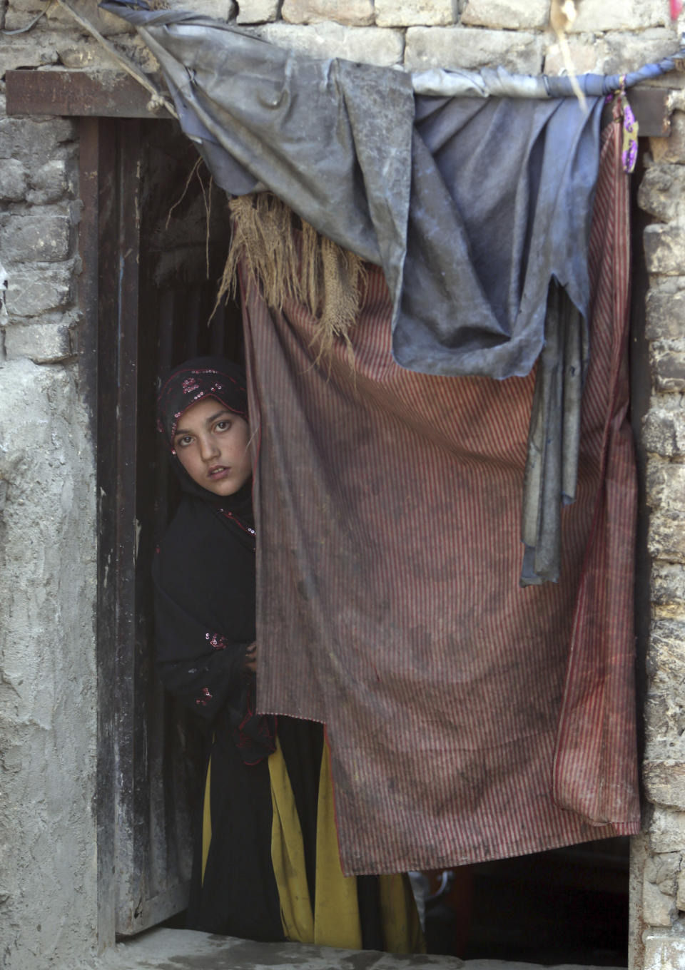 In this Sunday, March 19, 2017 photo, a young women looks on through a door in her home in Kabul, Afghanistan, Sunday, March 19, 2017. An aid group says nearly a third of all children in war-torn Afghanistan are unable to attend school, leaving them at increased risk of child labor, recruitment by armed groups, early marriage and other forms of exploitation. (AP Photos/Massoud Hossaini)