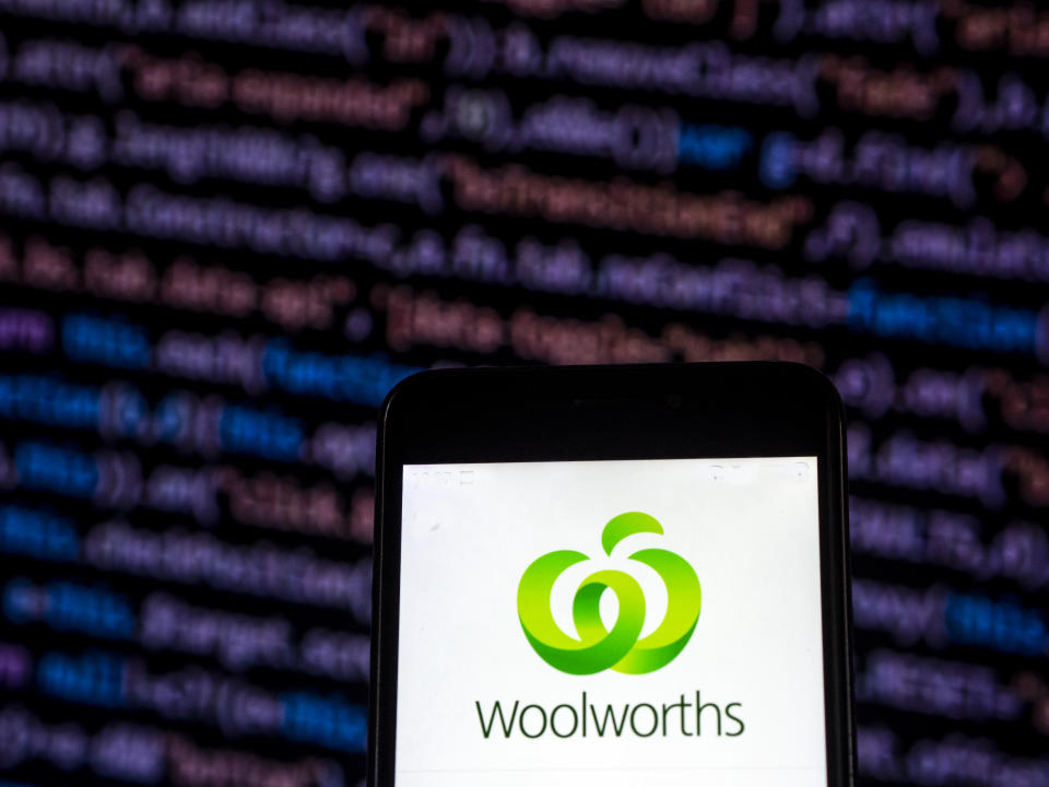 Woolworths app on phone in front of coding screen on computer. Source: Getty Images