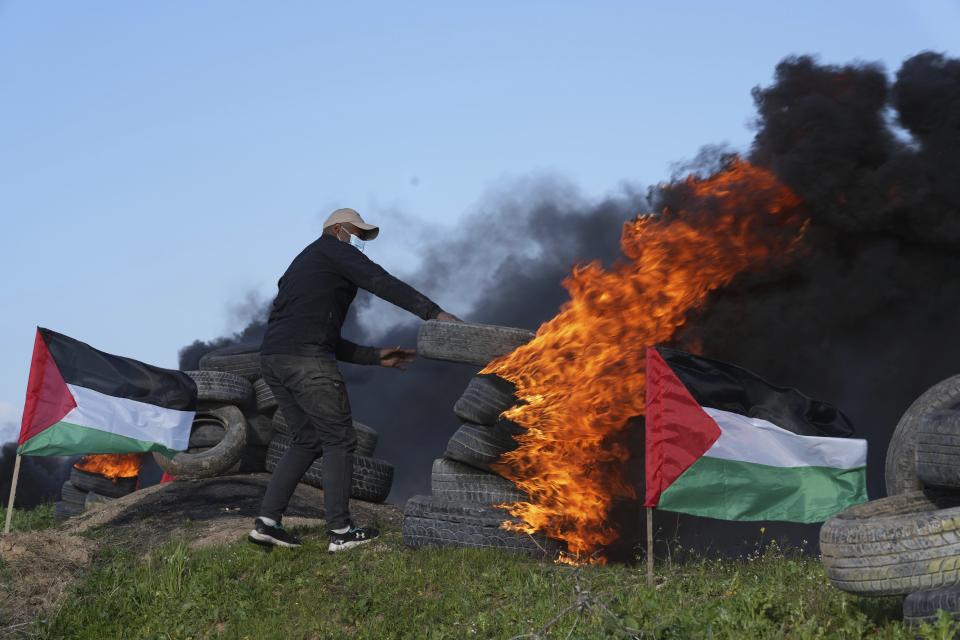 A demonstrator burns tires during a protest against Israeli military raid in the West Bank city of Nablus, along the border fence with Israel, in east of Gaza City, Wednesday, Feb. 22, 2023. Palestinian officials say several Palestinians have been killed and over a hundred were wounded during a rare daytime Israeli army arrest raid in the occupied West Bank. The Palestinian Health Ministry says a 72-year-old man was among the dead. The raid took place on Wednesday in the city of Nablus, a scene of frequent military activity. (AP Photo/Adel Hana)