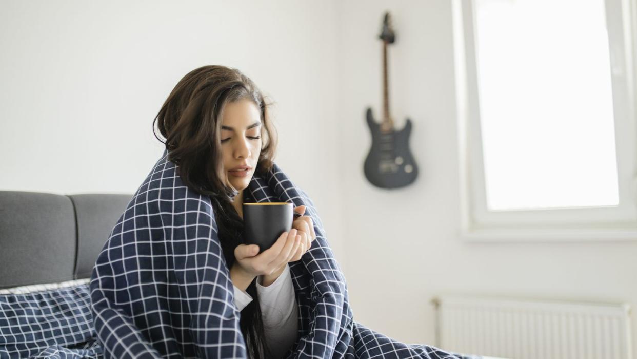 sick woman lying in bed with high fever cold flu and migraine