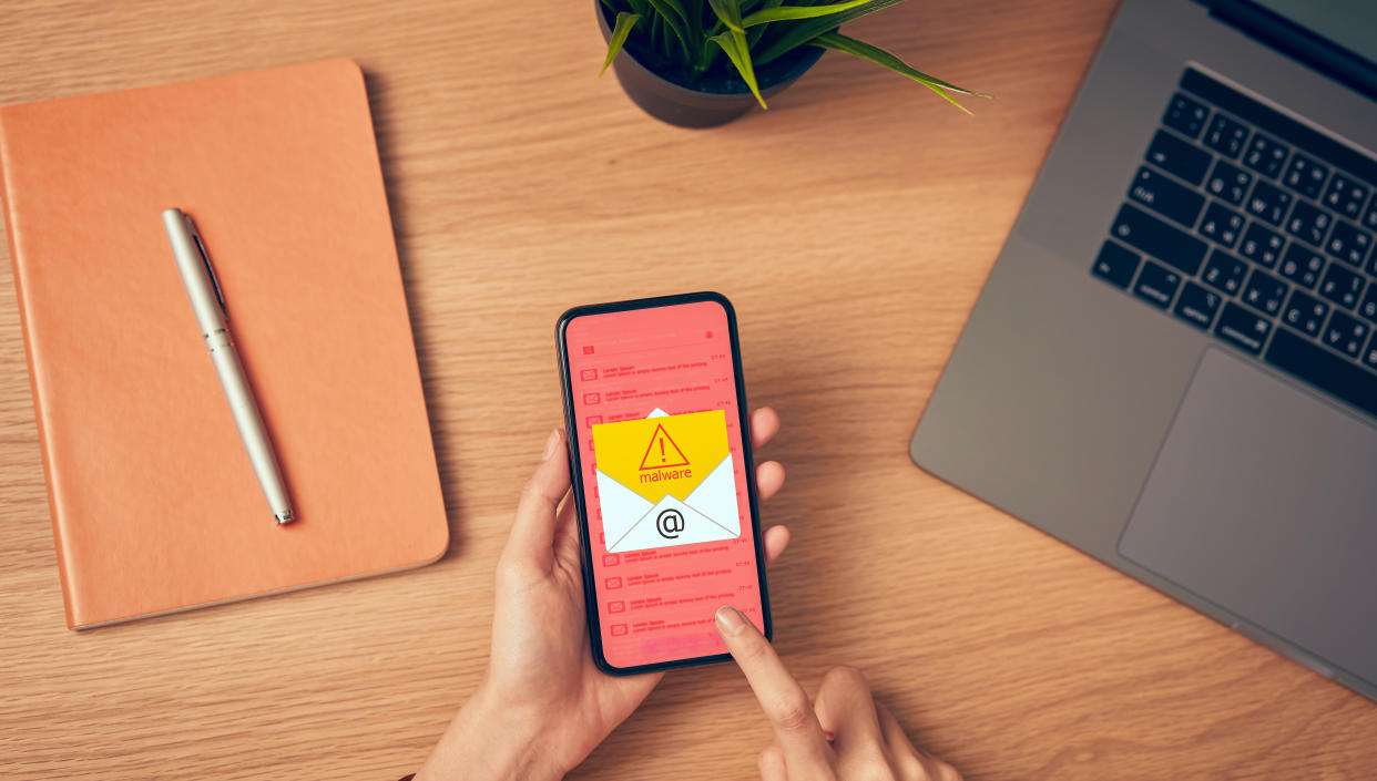 Concept of cyber crime, hand holding smartphone and show malware screen that comes with email, hack password from bank accounts and personal data. Photo: Getty