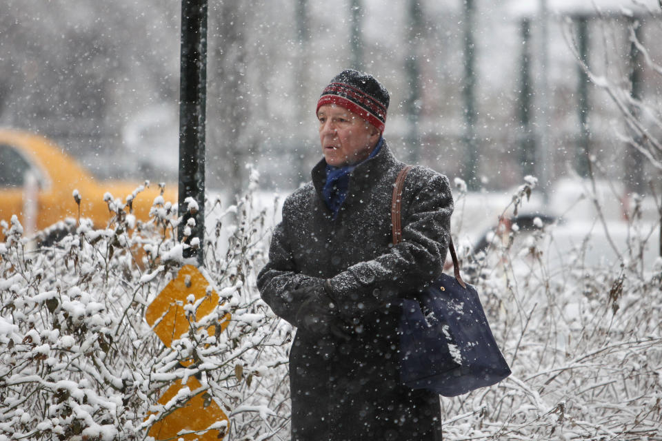 A man waits for the bus as wet snow falls Monday, Feb. 3, 2014, in New York. The National Weather Service says the storm could bring up to 8 inches of snow Monday to New York. (AP Photo/Jason DeCrow)