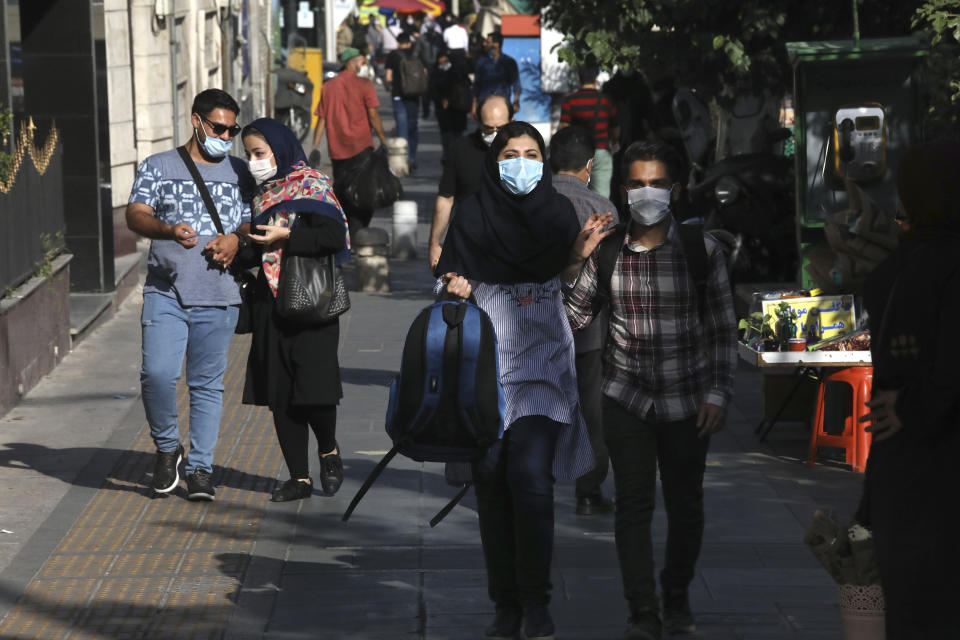 People wearing protective face masks to help prevent the spread of the coronavirus walk on a sidewalk in downtown Tehran, Iran, Sunday, Sept. 20, 2020. Iran's president dismissed U.S. efforts to restore all U.N. sanctions on the country as mounting economic pressure from Washington pushed the local currency down to its lowest level ever on Sunday. (AP Photo/Vahid Salemi)