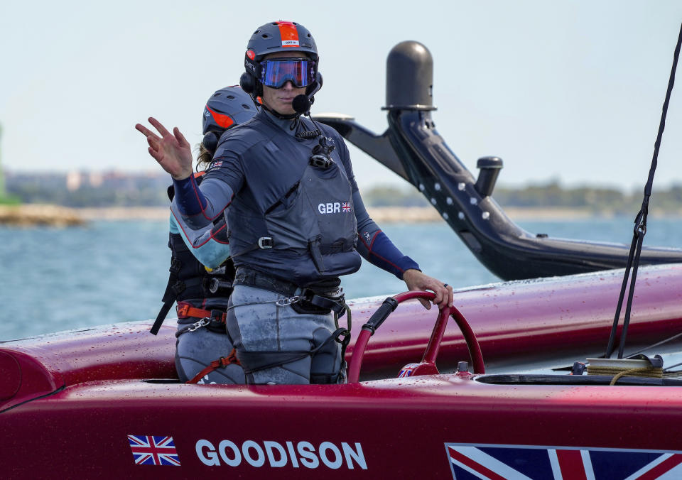 In this photo provided by SailGP, Paul Goodison, interim helmsman of Great Britain SailGP Team, waves from the helm during practice in Taranto, Italy, June 1, 2021. The SailGP global road show touches down in Old Blighty this weekend, giving Goodison the opportunity to sail in front of home crowds for the first time since the 2012 London Olympics. The regatta on Plymouth Sound will also give Australia's Tom Slingsby the chance to bounce back from a last-place performance in the previous regatta, an unthinkable finish for the crack team that claimed the $1 million, winner-take-all prize during the inaugural season of 2019. (Bob Martin/SailGP via AP)