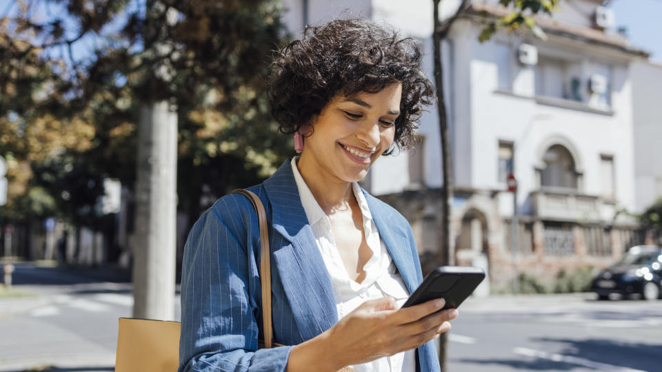 Woman walking, smiling and looking at her phone