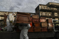 Workers collect and stack the coffins of people that have been recently cremated amid the new coronavirus pandemic, at the La Recoleta cemetery in Santiago, Chile, Sunday, June 28, 2020. The coffins are collected, destroyed, and processed by a company specialized in organic waste. (AP Photo/Esteban Felix)