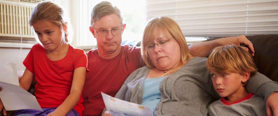 Unhappy Family Sitting On Sofa Looking At Bills