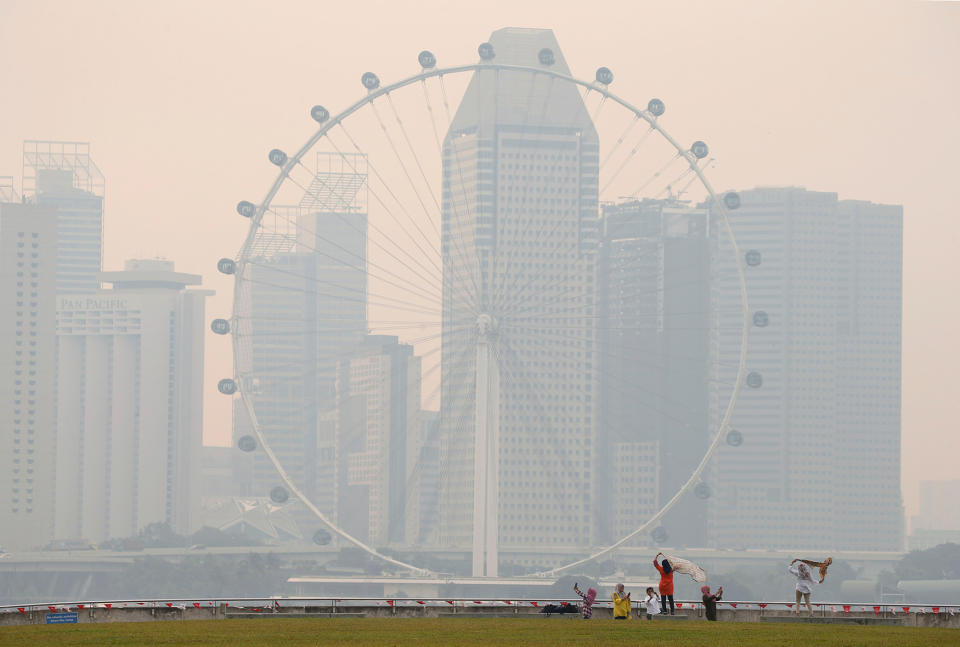 <p>People take photos near the Singapore Flyer observatory wheel shrouded by haze Aug. 26, 2016. (Photo: Edgar Su/Reuters) </p>