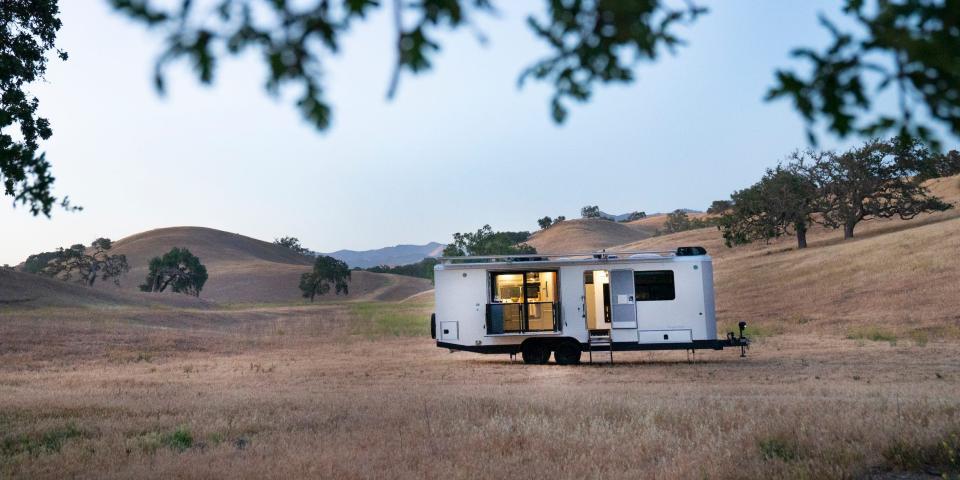 The exterior of the travel trailer as it sits on a brown field.