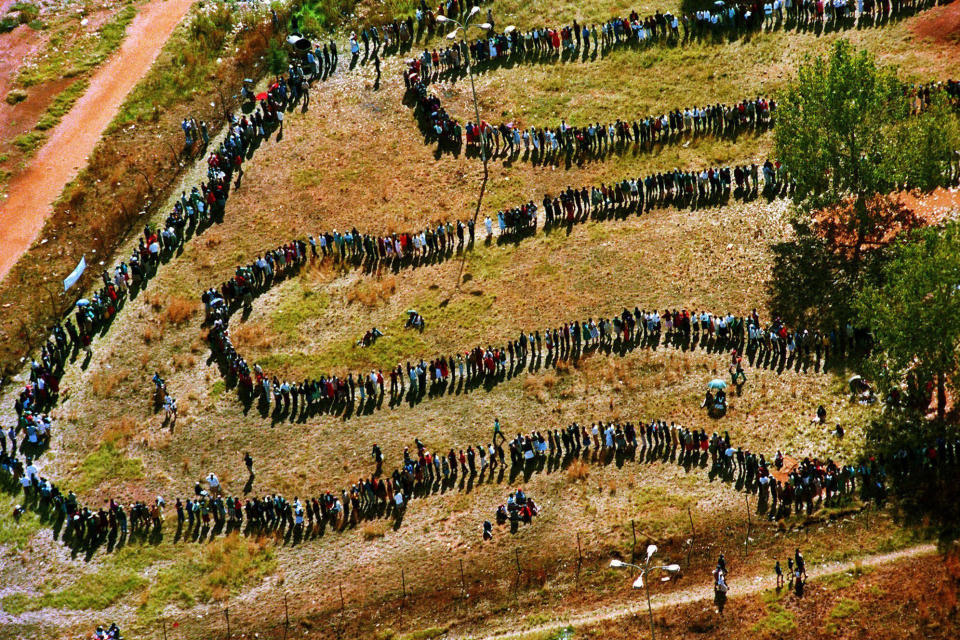En esta imagen de archivo, cientos de personas esperan en fila para votar en Soweto, Sudáfrica, en las primeras elecciones abiertas del país, el 27 de abril de 1994. (AP Foto/Denis Farrell. archivo)