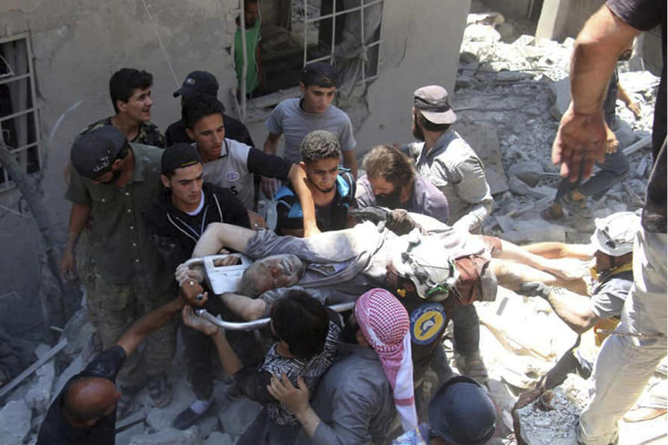 This photo provided by the Syrian Civil Defense White Helmets, which has been authenticated based on its contents and other AP reporting, shows Syrian White Helmet civil defense workers and civilians carry an injured man on a stretcher after an airstrike hit the northern town of Ariha, in Idlib province, Syria, Saturday, July 27, 2019. Syrian activists and a doctor say a government airstrike killed several people when it hit a weekly open-air market in a busy town in the last rebel stronghold in northwestern Syria. (Syrian Civil Defense White Helmets via AP)