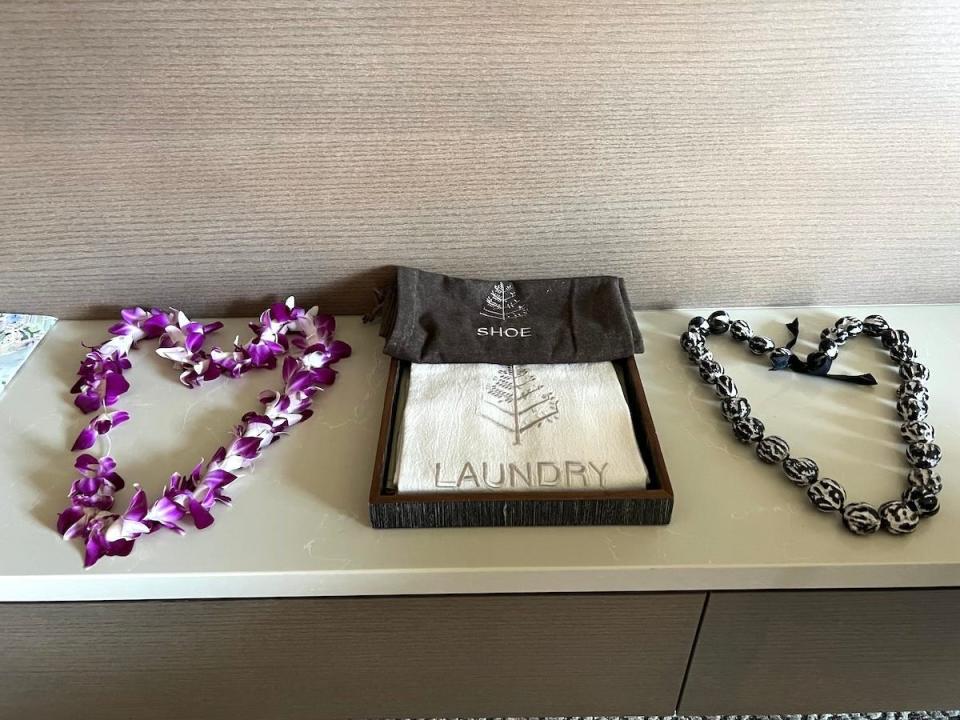 Leis arranged in heart shapes, on either side of a caddy holding a laundry and shoe bag, in a guestroom at the Four Seasons Maui at Wailea.