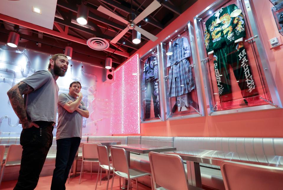 Post Malone and Raising Cane’s founder Todd Graves show media around a remodeled Raising Cane’s Restaurant, designed by the singer, in Midvale on Thursday, April 13, 2023. Outfits that Post Malone wore on tour hang on the wall. | Kristin Murphy, Deseret News